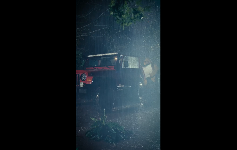 Extracted frame from the Jurassic Park Jeep teaser showing the vehicle in heavy rain