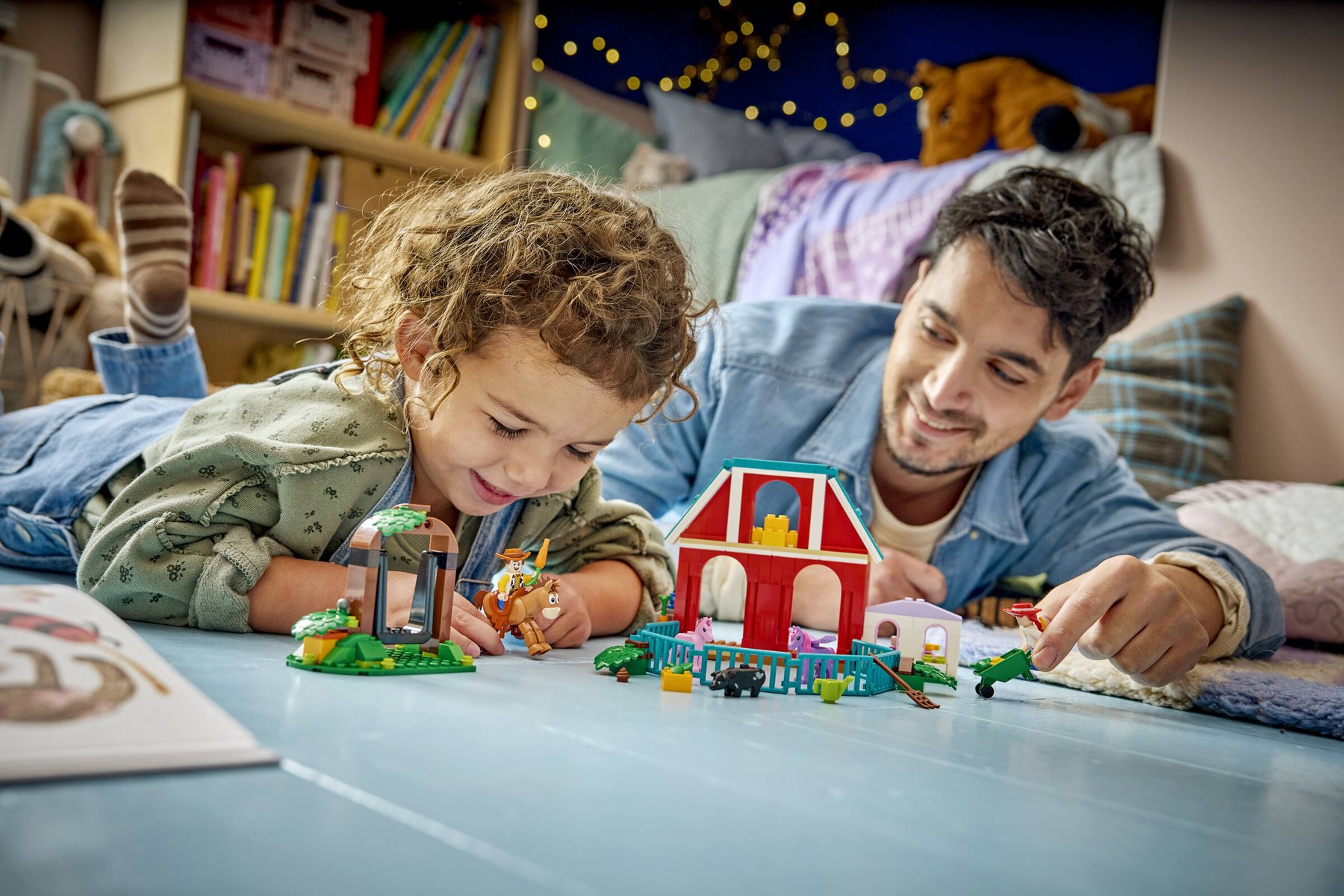 A child and an adult holding minifigures and playing with LEGO® ǀ Disney and Pixar Toy Story 5 Blaze’s Horse Ranch.