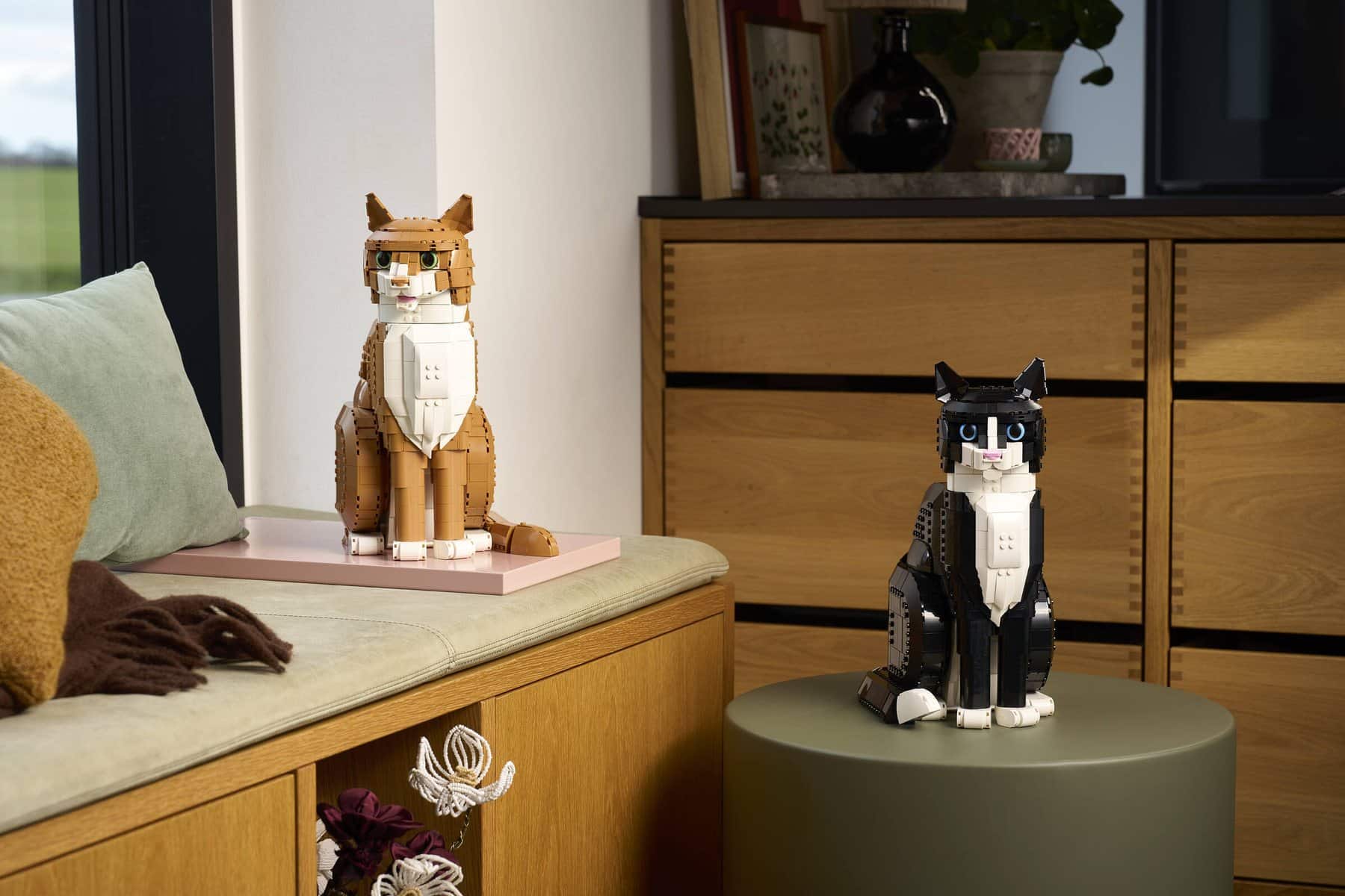 Official LEGO lifestyle image of LEGO Ideas 21349 Tuxedo Cat and 21376 Orange Cat in home-oriented presentation