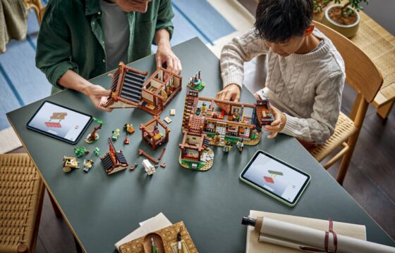 A man and a boy sitting at a table, using tablets to build a LEGO® Chinese Festivals Ancient Moon-Gazing Inn together.