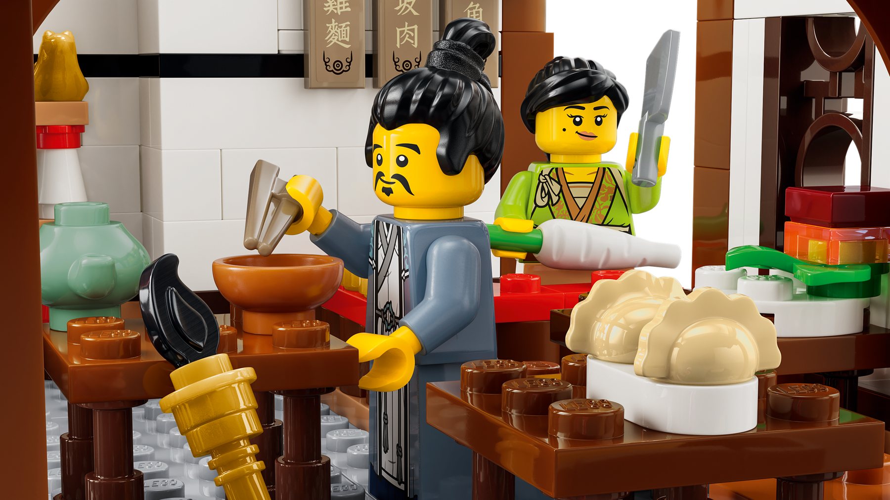 A kitchen scene with 1 minifigure holding chopsticks over a bowl and another holding a knife over a vegetable.
