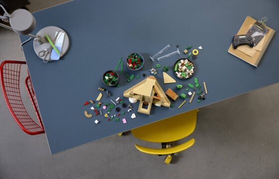 Aerial view of a partially built LEGO® Pokémon™ Rayquaza at a table showing small parts scattered and in trinket dishes.