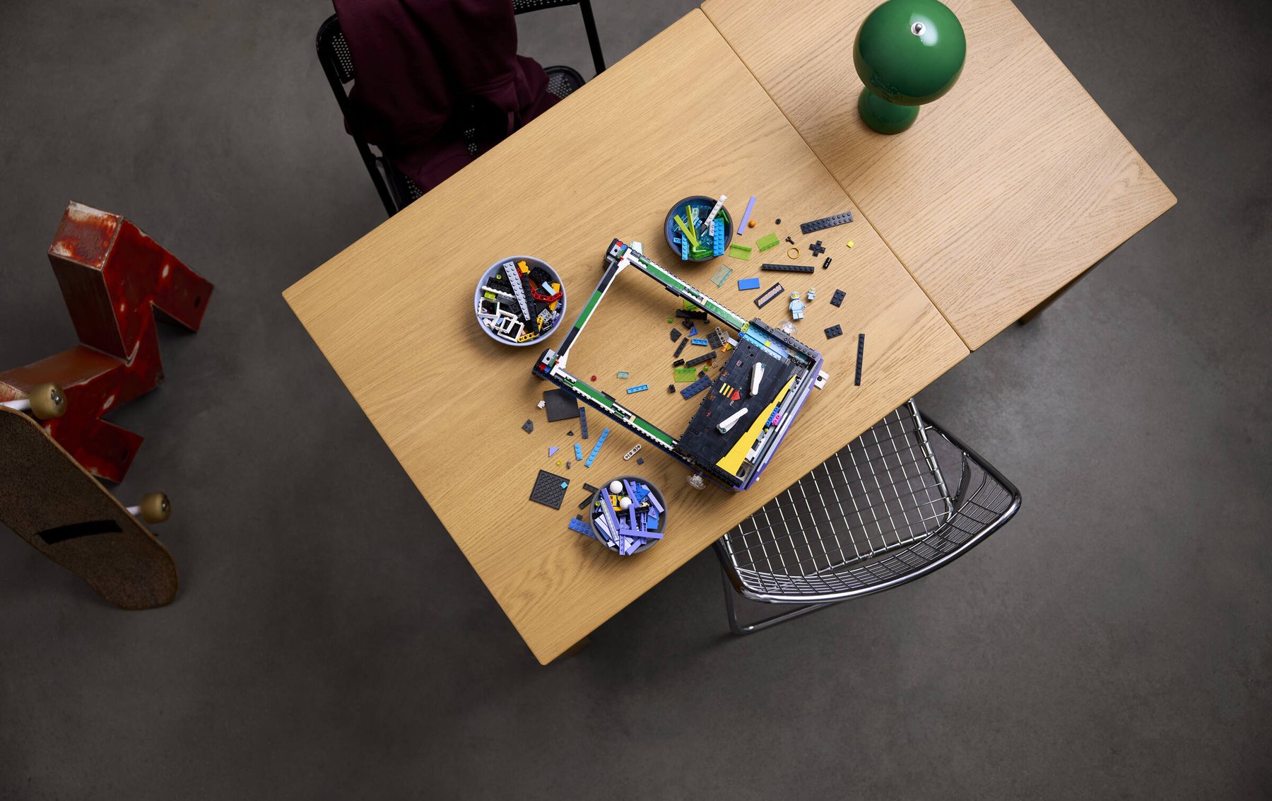 Aerial view of a partially built LEGO® Icons Arcade Pinball Machine set, parts scattered across a table.