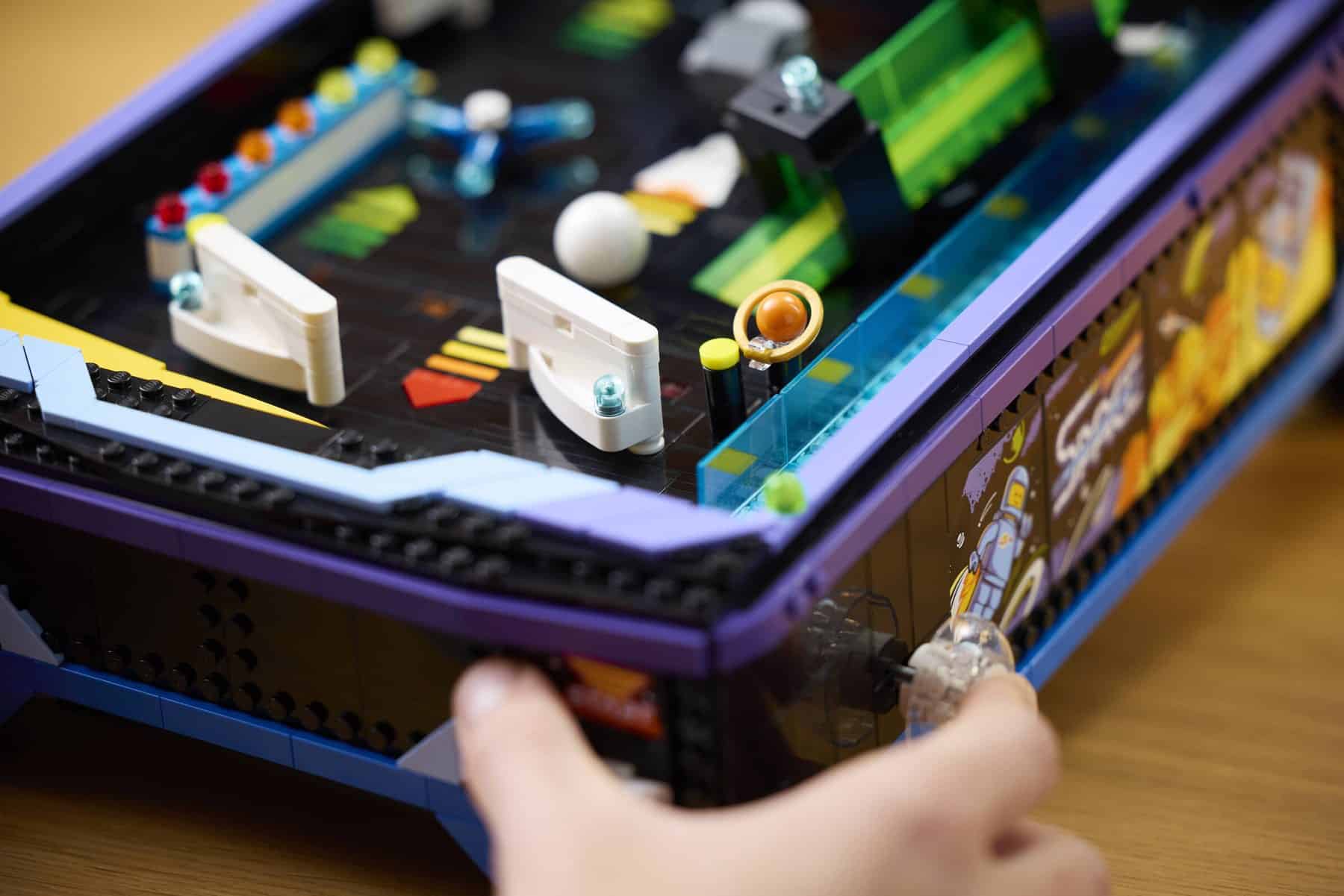 A person using the spring-powered launcher on a LEGO® Icons Arcade Pinball Machine set to play the game.