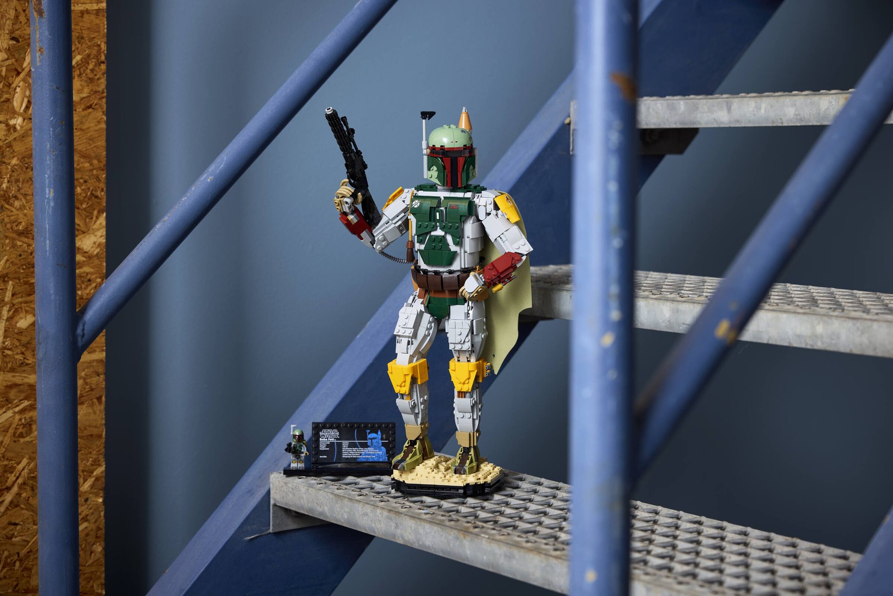 Built LEGO® Star Wars™ Boba Fett and info plaque with minifigure displayed on a blue metal staircase.