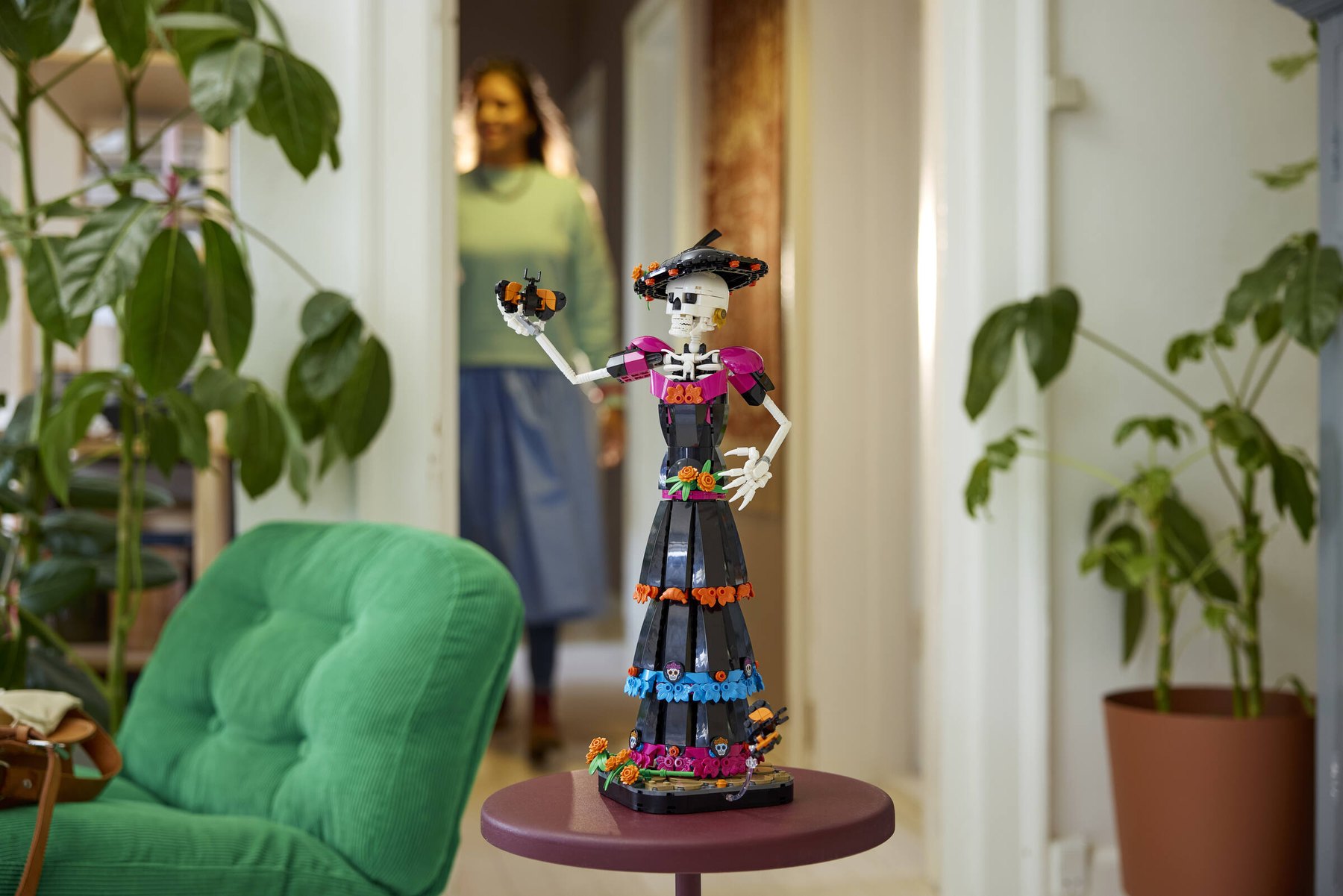 LEGO® Ideas La Catrina set showing a skeleton figure holding a brick-built butterfly, displayed on a table.