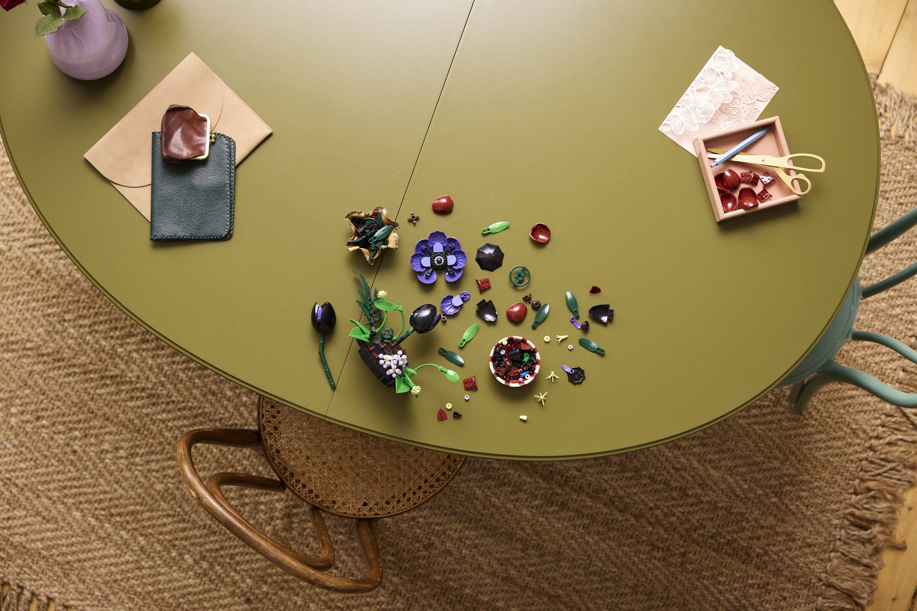 Aerial view of a partially built LEGO® Botanicals Dark Flower Arrangement set with parts scattered across a table.