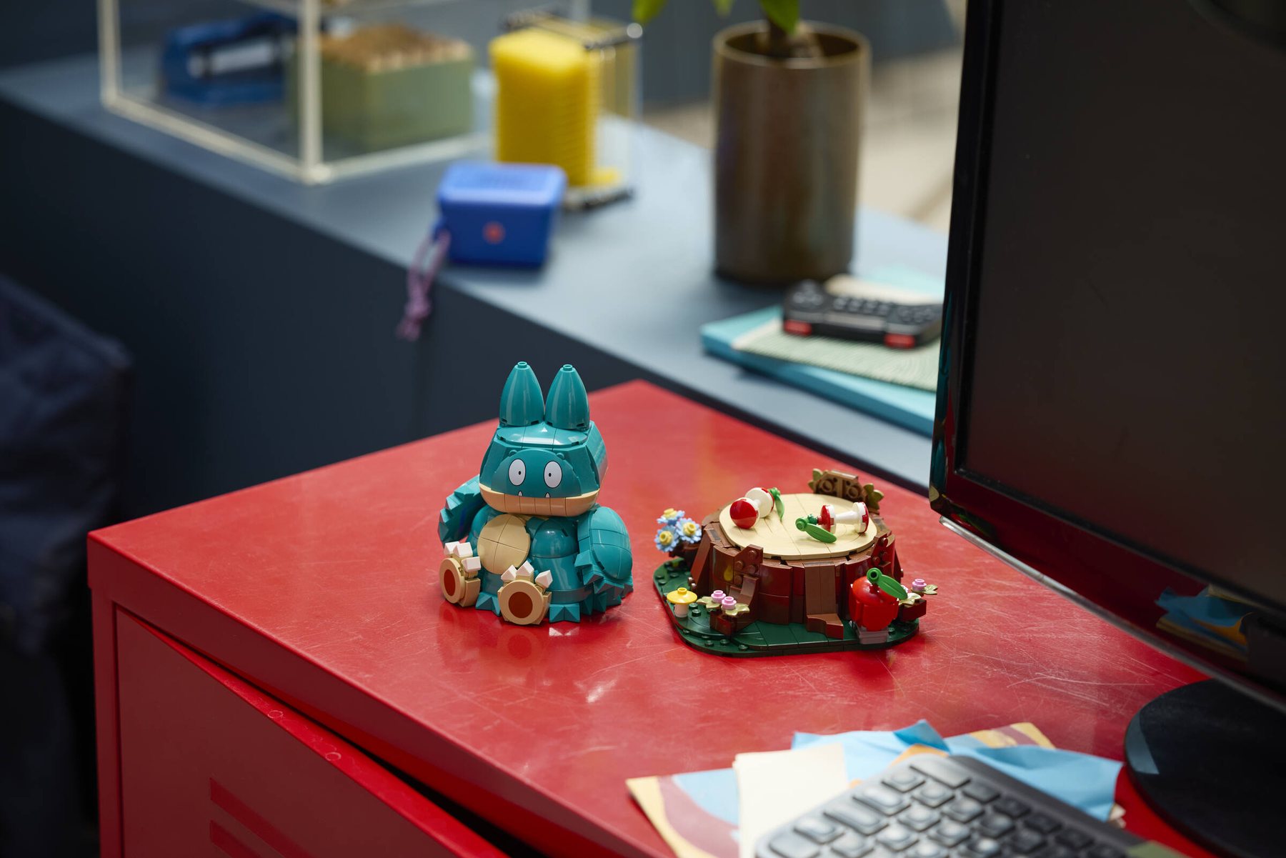 LEGO® Pokémon™ Munchlax shown next to its baseplate, displayed on top of a red metal sideboard.