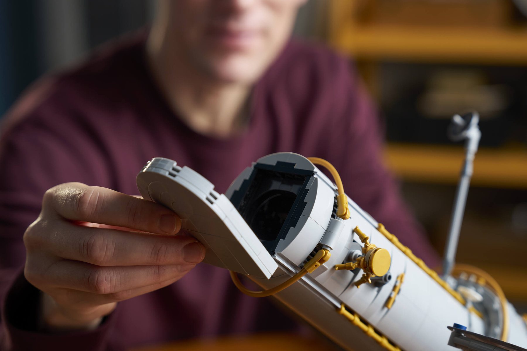 Close-up of a man opening the aperture door on a LEGO® Icons Hubble Space Telescope.
