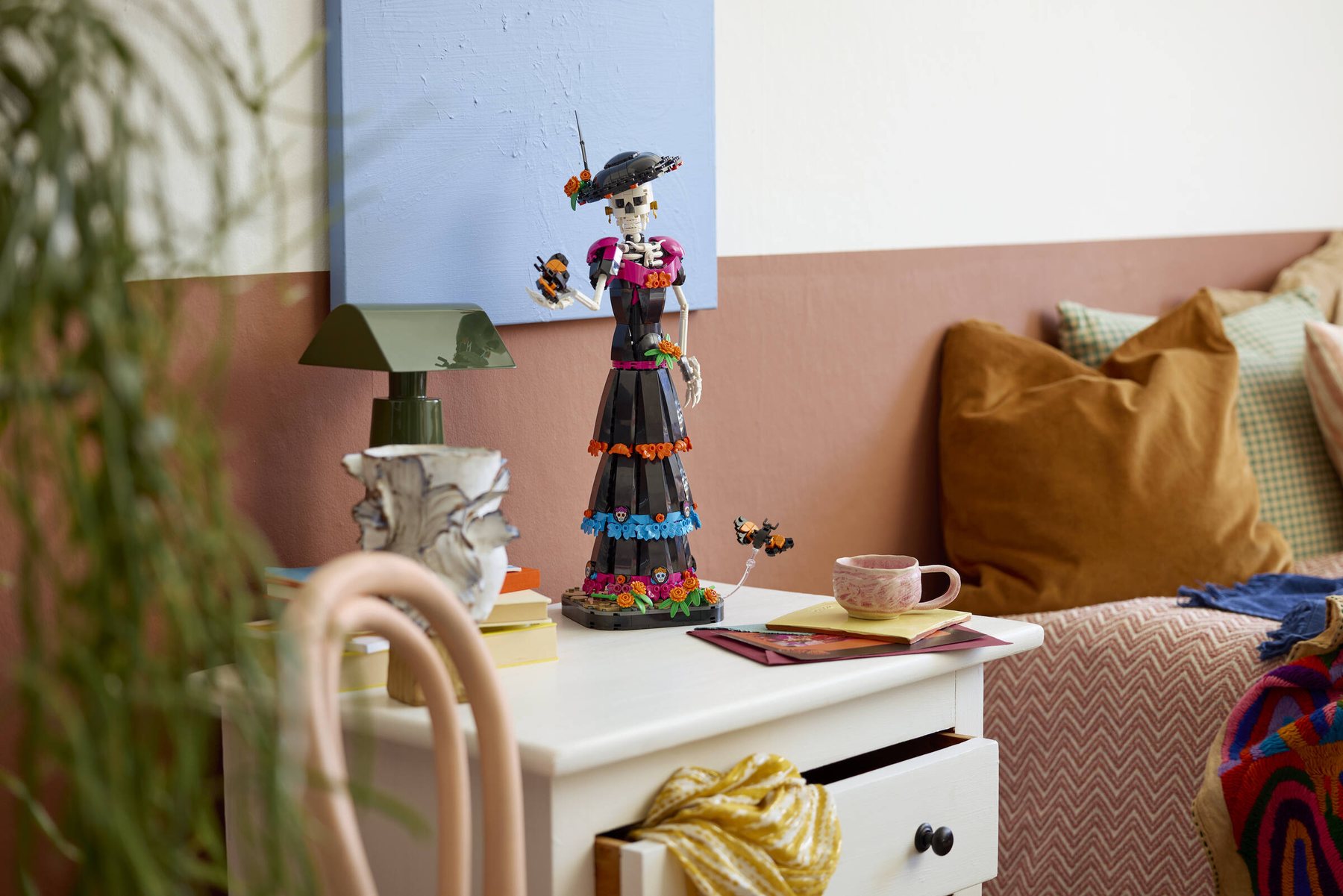 LEGO® Ideas La Catrina set showing a skeleton figure holding a marigold flower, displayed on a chest of drawers.