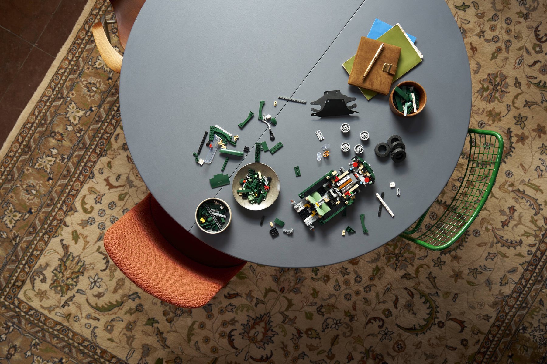 Aerial view of a partially built LEGO® Icons Jaguar E-Type set on a table, with parts and bowls of LEGO bricks nearby.
