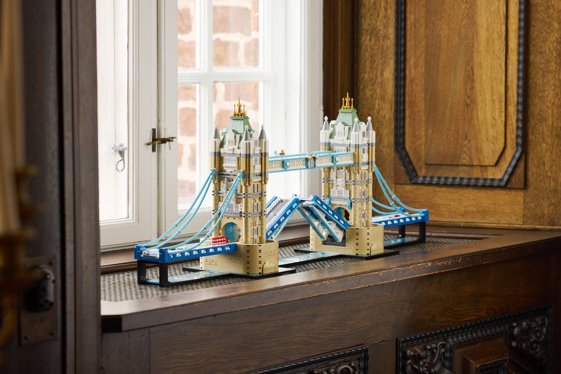 LEGO® Architecture Tower Bridge set displayed on a windowsill, next to white wooden windows.