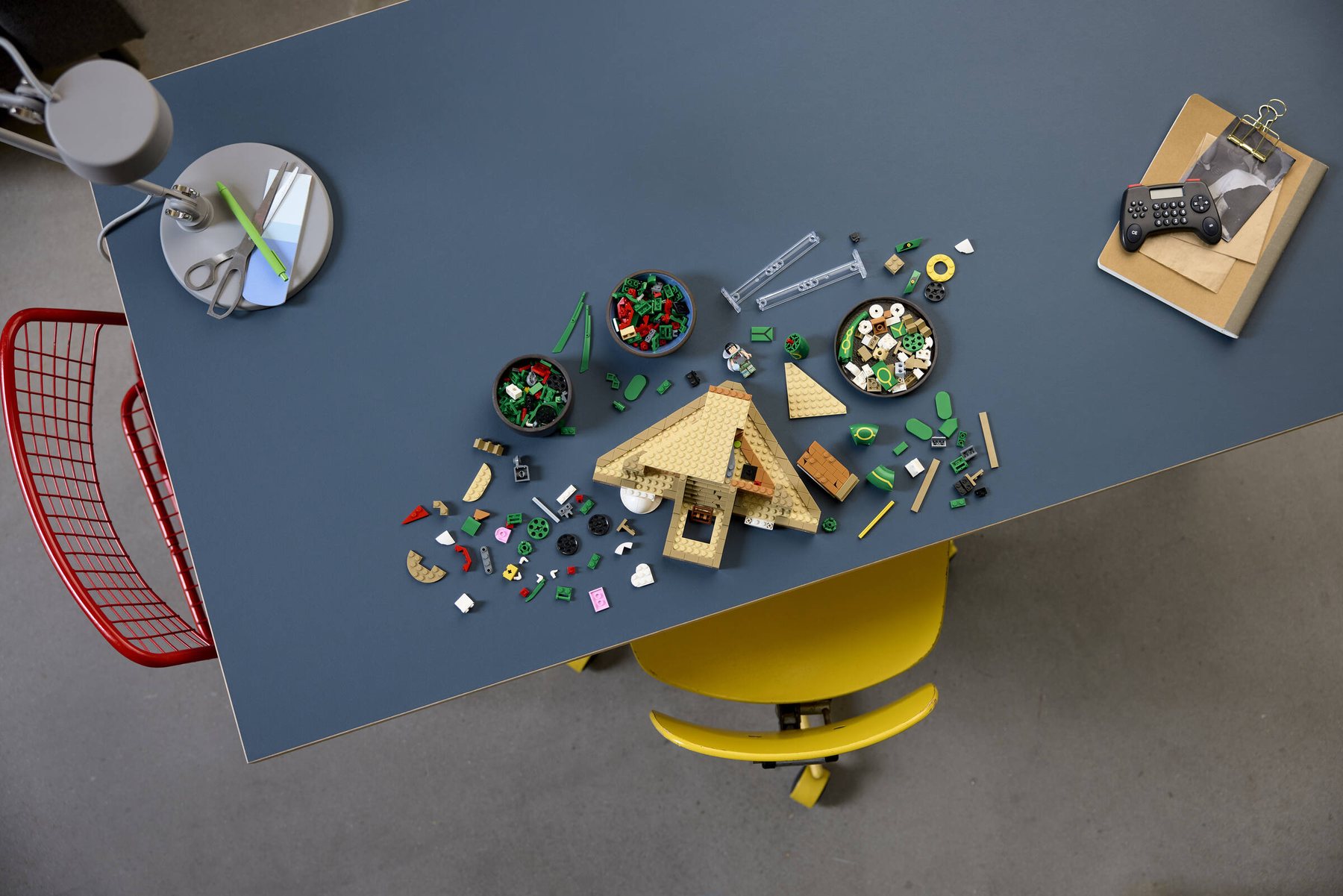 Aerial view of a partially built LEGO® Pokémon™ Rayquaza at a table showing small parts scattered and in trinket dishes.