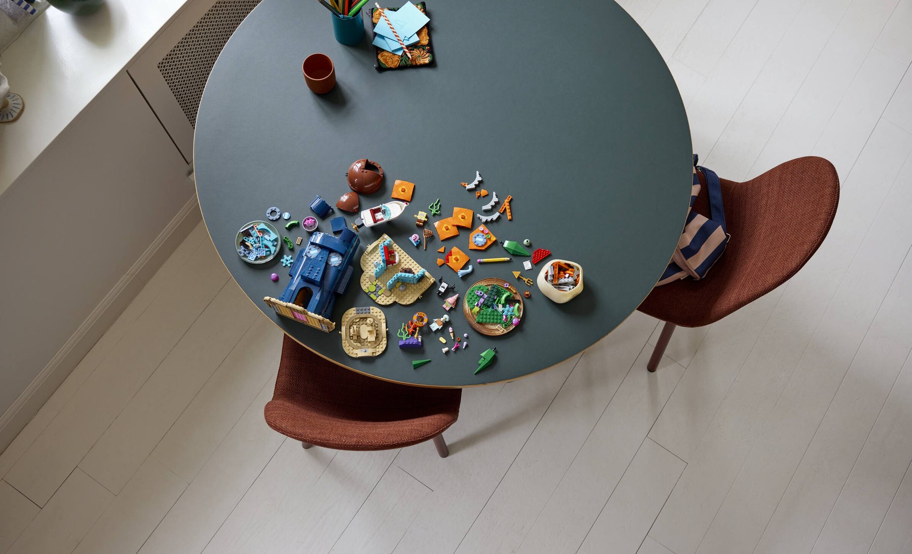 Aerial view of a partially built LEGO® Icons SpongeBob SquarePants: Bikini Bottom set scattered across a table.