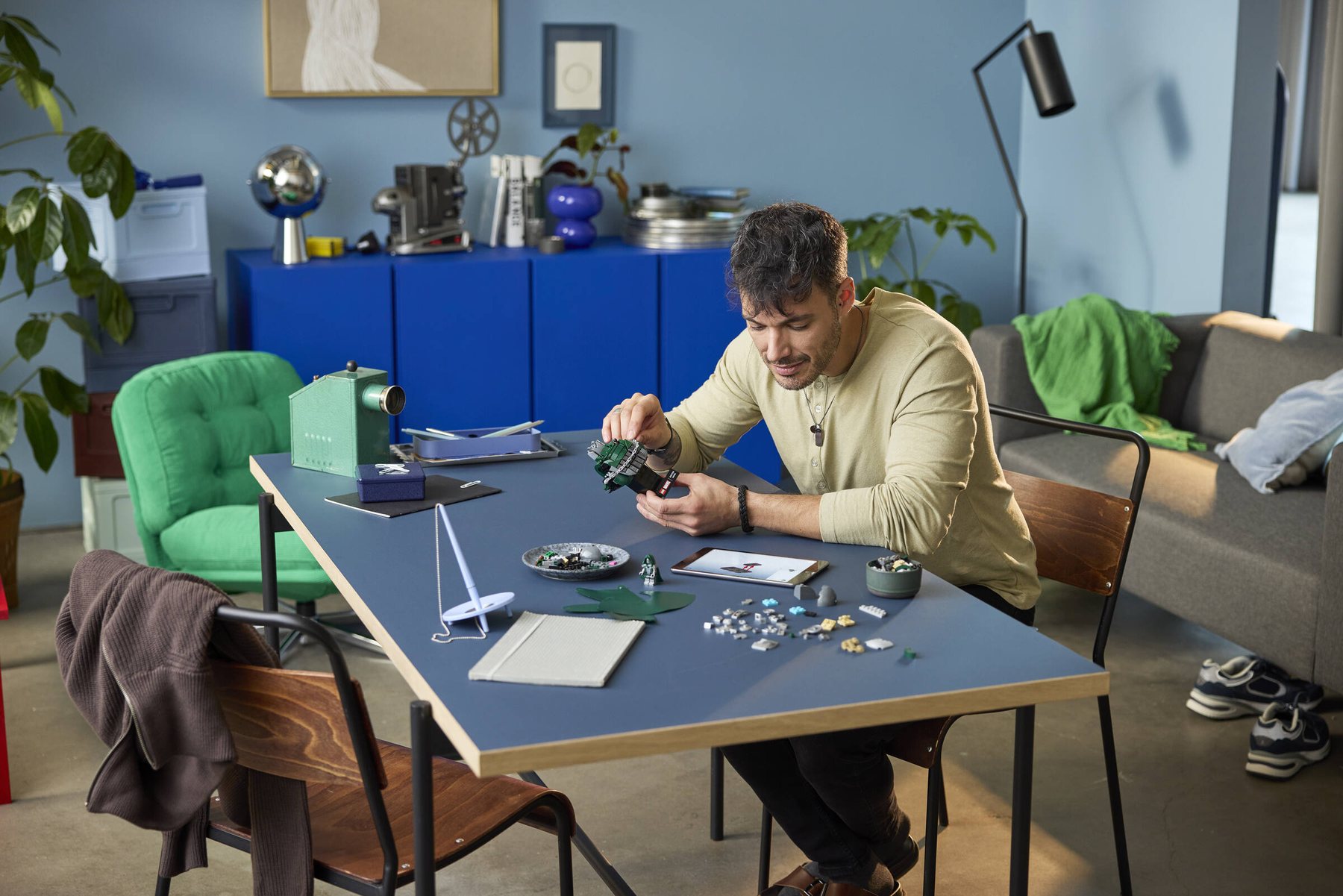 A man sitting at a table following building instructions on a tablet while assembling a LEGO® ǀ Marvel Doctor Doom Bust.