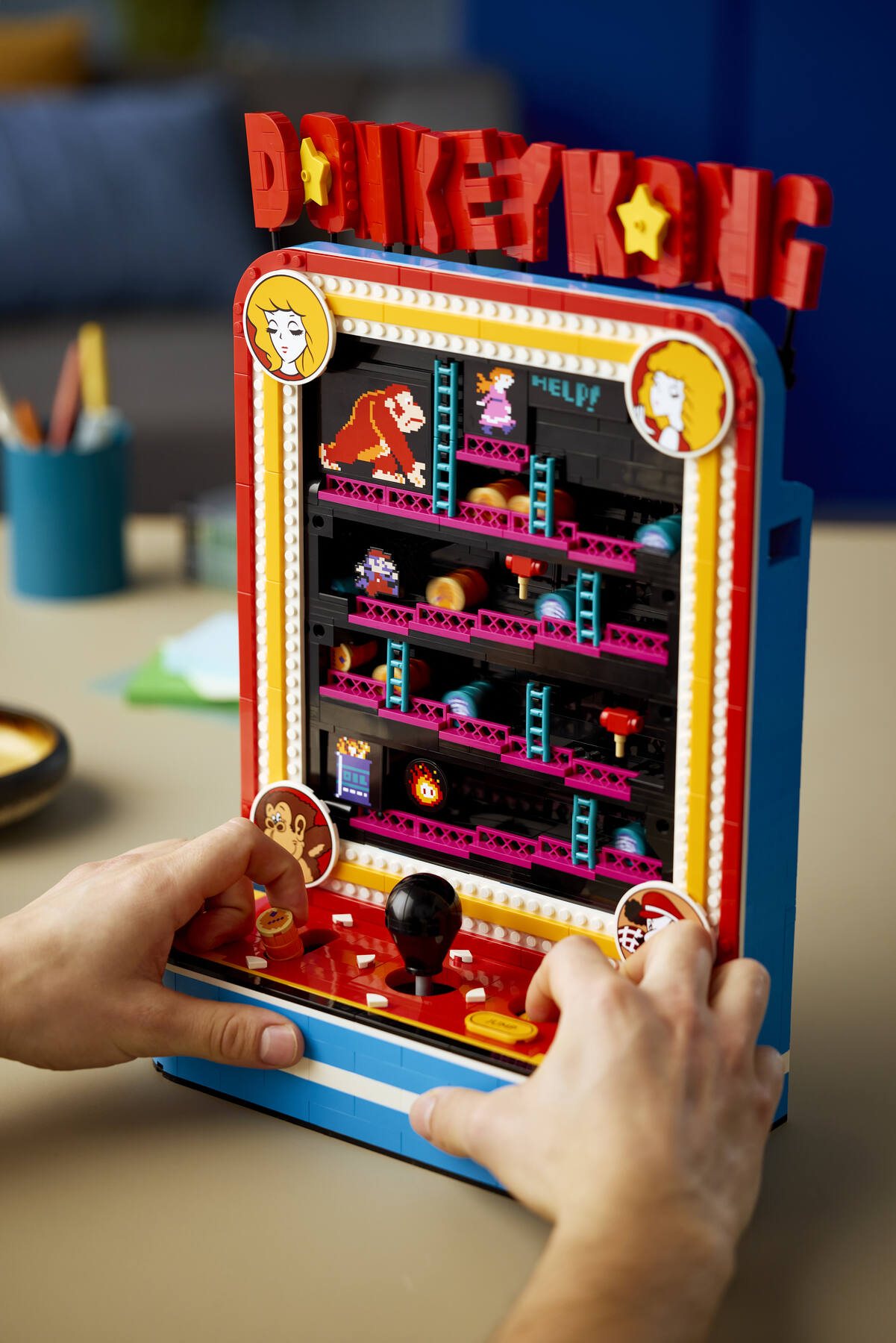 Close-up of hands pressing the buttons on a LEGO® Donkey Kong™ Arcade set to activate the moving parts.