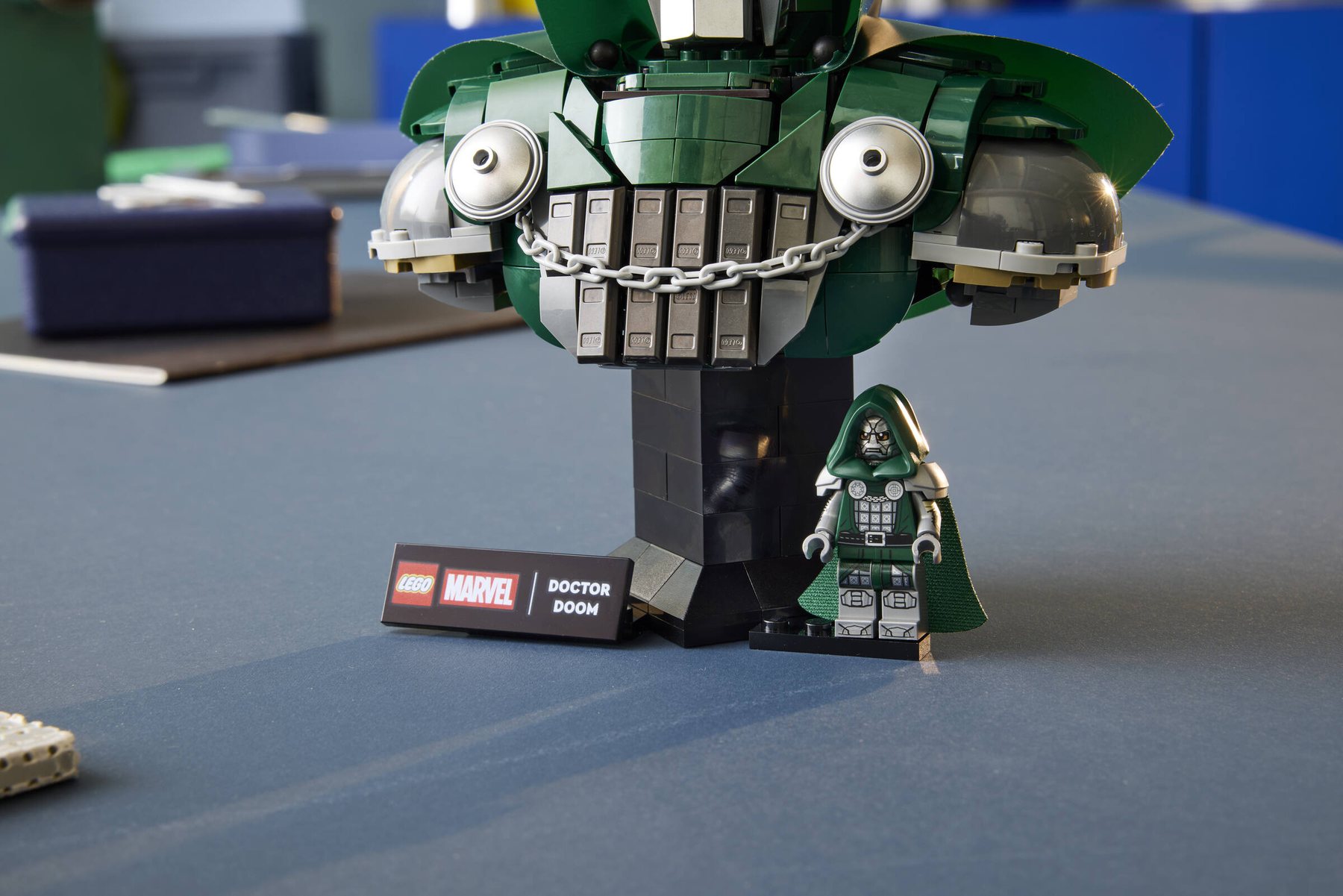 Close-up of a LEGO® ǀ Marvel Doctor Doom Bust's stand showing the set's nameplate and a Doctor Doom minifigure.
