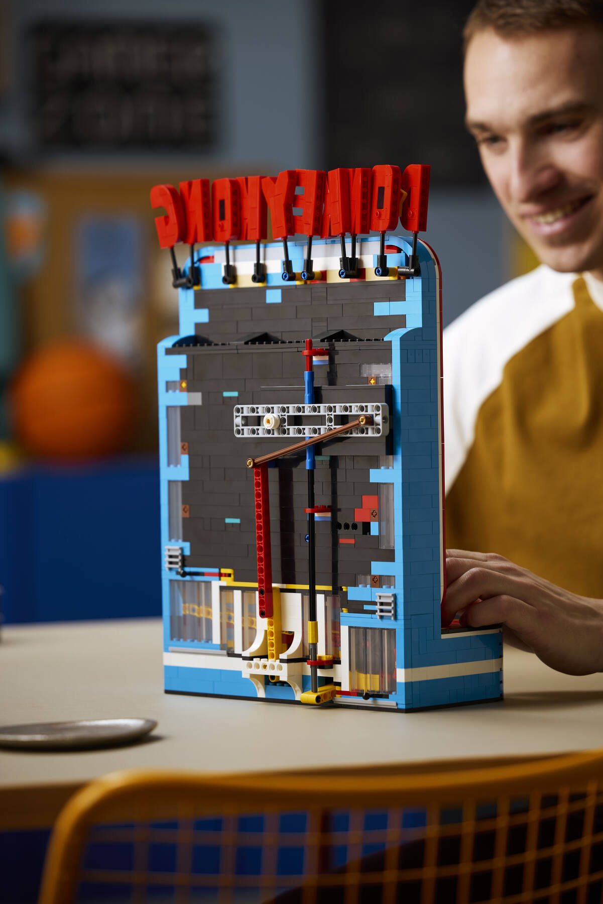 Rear view of a LEGO® Donkey Kong™ Arcade set with a man playing the game visible in the background.